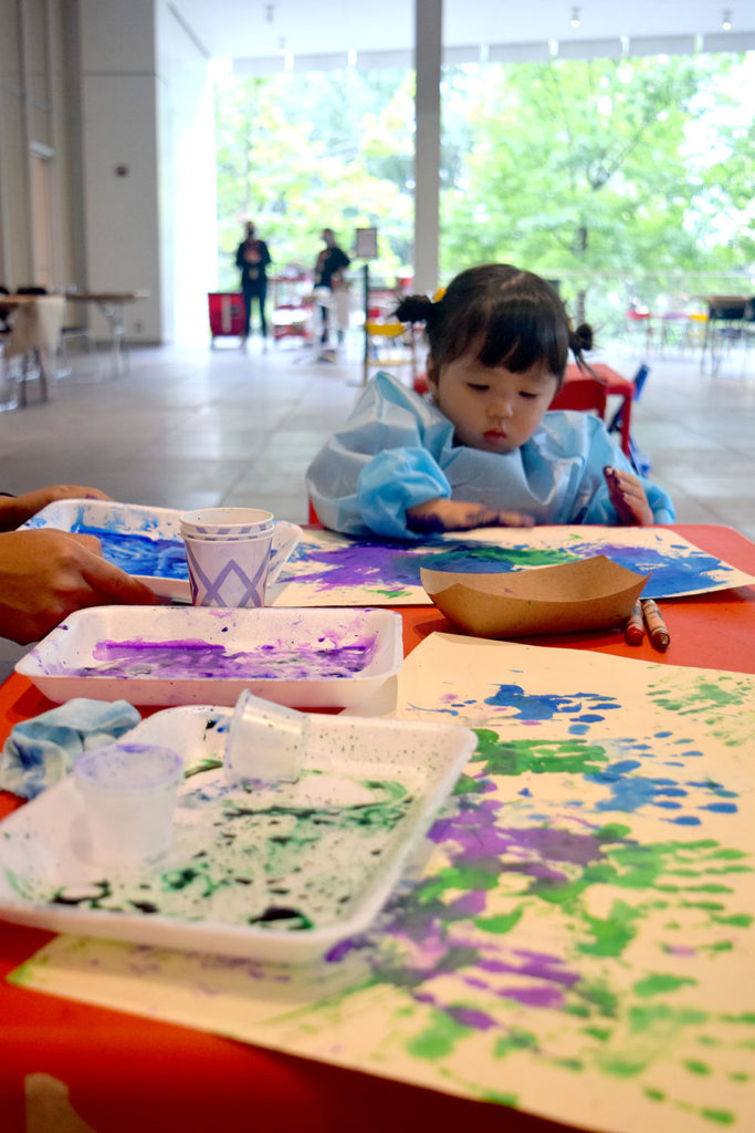 A toddler makes a finger painting.