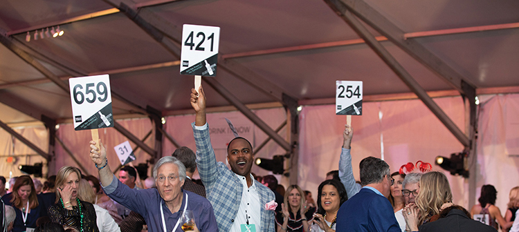 Guests hold up paddles at auction