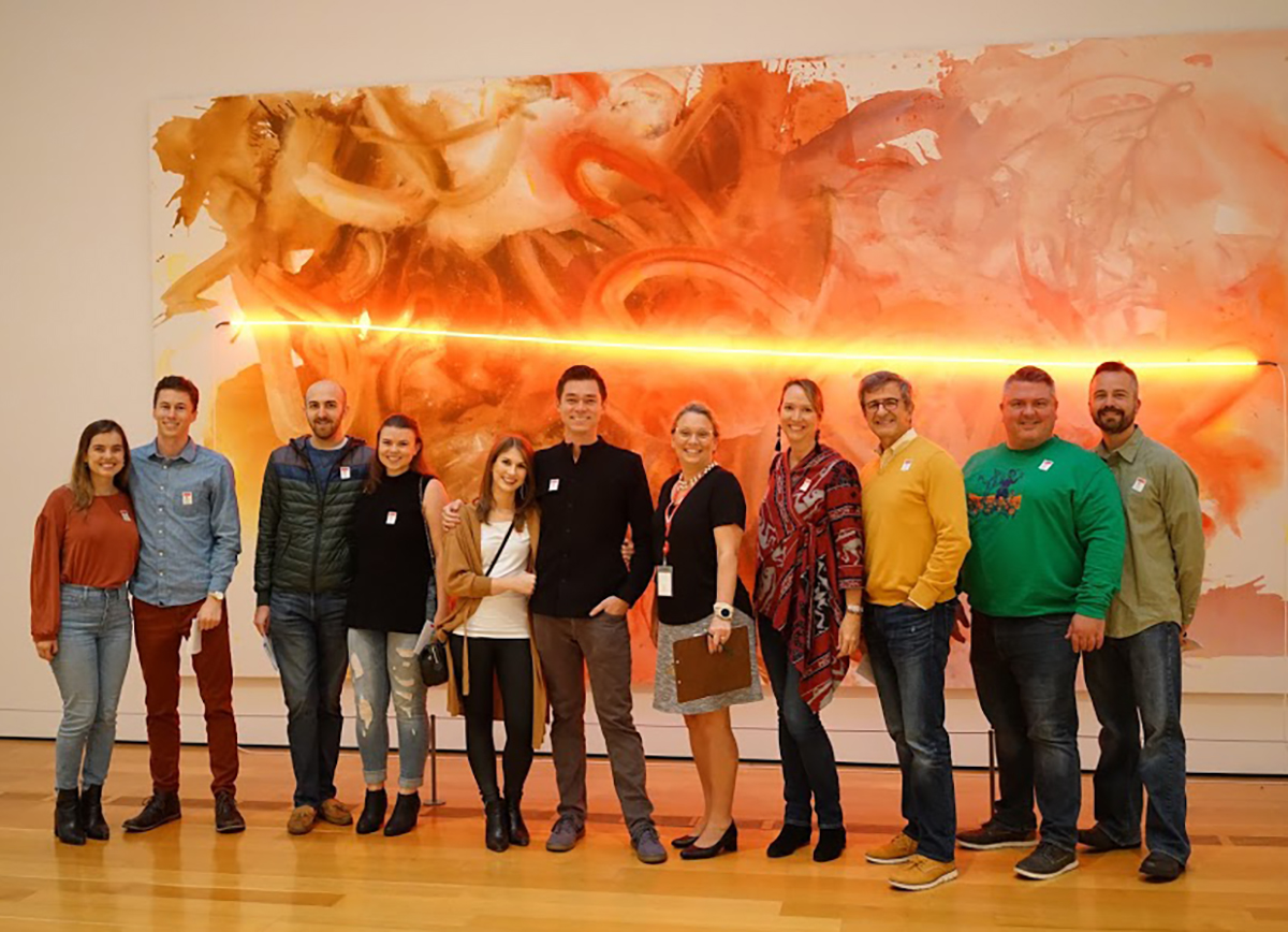 A group of people pose in front of a painting