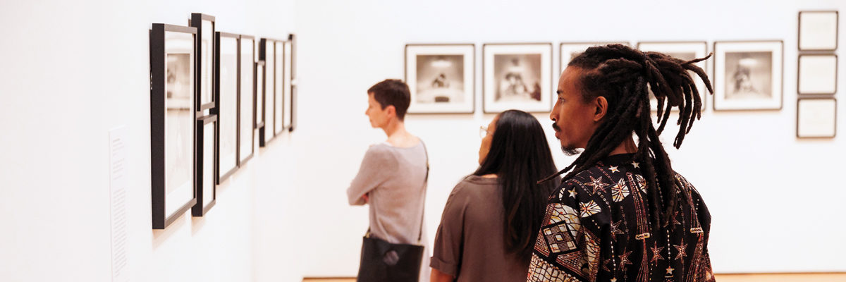 A image showing visitors in a gallery viewing Carrie Mae Weems's The Kitchen Table Series.